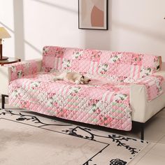 a dog laying on top of a couch covered in pink and white quilted furniture