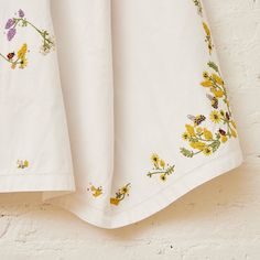 a white sheet with yellow and purple flowers on it hanging from the side of a brick wall