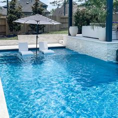 an empty swimming pool with lounge chairs and an umbrella in the middle is pictured here