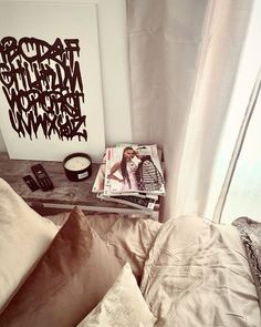 a magazine is sitting on top of a bed next to some pillows and a phone