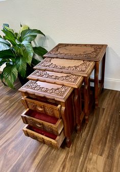 a set of three wooden tables sitting on top of a hard wood floor next to a potted plant