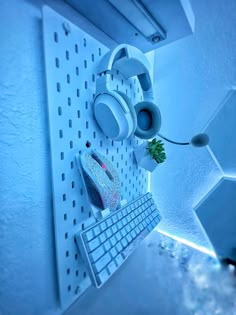 a computer keyboard sitting on top of a white shelf next to a mouse and plant