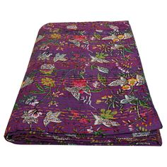 a purple blanket with colorful flowers and birds on the front, along with white background