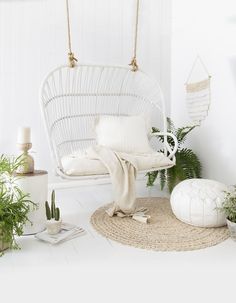 a white hanging chair in a room with potted plants