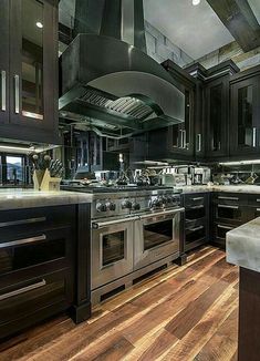 a large kitchen with black cabinets and stainless steel appliances