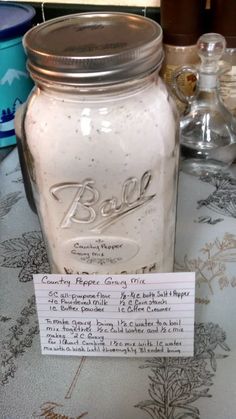 a glass jar sitting on top of a table next to a paper label that says ball