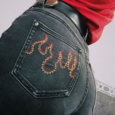 the back of a woman's jeans with snake embroidered on it and her hand in her pocket