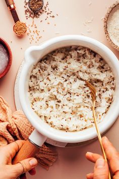 someone is spooning rice into a bowl with other ingredients around it on a pink surface