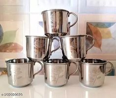 a stack of silver cups sitting on top of a white counter