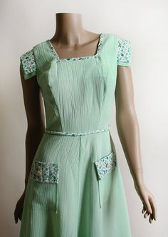 "FREE DOMESTIC SHIPPING! <3 ♥ Lovely vintage 1970s mint green cotton dress, with floral accents! ♥ Buttons up the back! Fitted waist, with matching floral waist tie rope. ♥ Cap style sleeves, with floral flap accent. Matching trim on the front skirt pockets! ♥ Cotton, crepe textured. Semi-sheer, you'll probably want a slip under. ♥ In great condition! * measurements when flat * Bust - 19\" across Shoulders - 14\" across Waist - 13\" across Hips - 21\" across Bodice length - 16\" Length - 40\" Green Retro Vintage Dress, Green Vintage Style Dress For Summer, Green Vintage Dress For Summer, 1950s Style Green Vintage Dress For Spring, Green Lined Vintage Dress For Summer, Green Buttoned Dress For Garden Party, Retro Green Vintage Dress For Daywear, Vintage Green Dress For Garden Party, Green Retro Cotton Vintage Dress