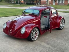 a very nice looking red car parked in the street with it's door open