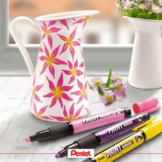 some pens are sitting next to a vase and flowers