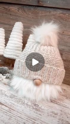 two knitted hats with white fur pom poms on them sitting next to each other