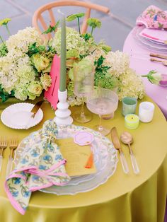 the table is set with plates, napkins and flowers