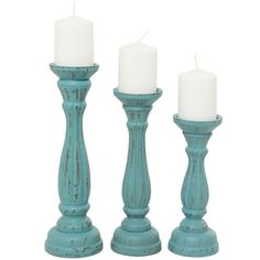 three teal candle holders with white candles