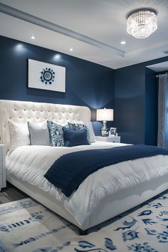 a blue and white bedroom with a large bed in the center, chandelier hanging from the ceiling