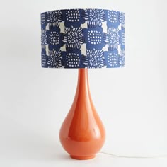 an orange table lamp with a blue and white shade on it's base, against a white background