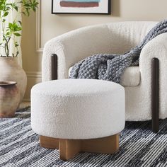 a white chair and ottoman in a room with a potted plant on the floor