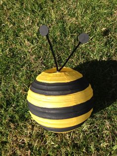 a yellow and black striped ball with two pins sticking out of it in the grass