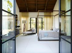 a bedroom with large windows and a bed in the middle, surrounded by glass doors