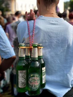 a woman is holding three beer bottles in her hand and the other one has a string attached to it