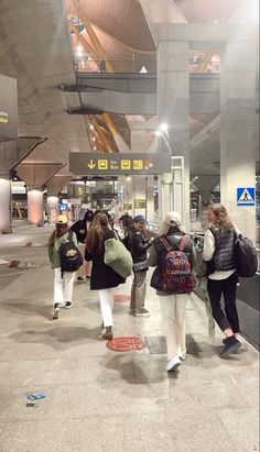 many people are standing in an airport waiting for their luggage