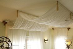 a bed with white drapes hanging over it's headboard and foot board