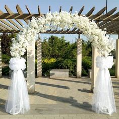 a wedding arch decorated with white flowers and ribbons