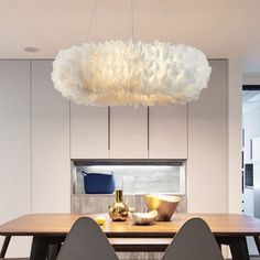 a dining room table with two chairs and a large light fixture hanging over it's head