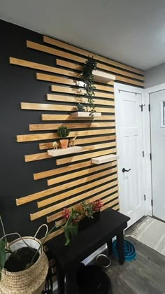 a black wall with wooden slats on it and some potted plants in the corner