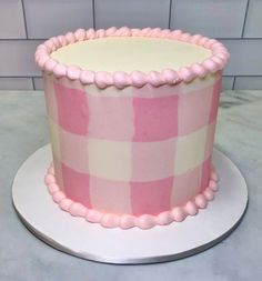 a pink and white cake sitting on top of a table next to a tile wall