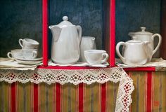 there are three white teapots and two cups on the shelf in front of each other