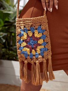 a woman is holding a crocheted bag with tassels