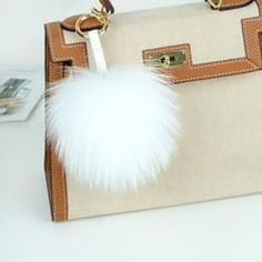 a handbag with a white fur ball hanging from it