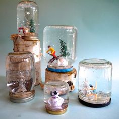 several glass jars filled with miniature figurines and snow globes