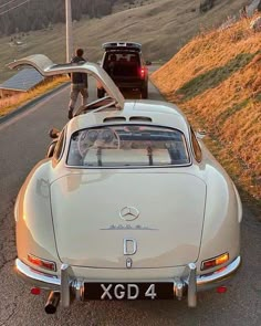 an old car is parked on the side of the road with it's trunk open