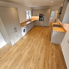 an empty kitchen with wood floors and white cabinets