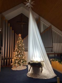 a christmas tree in the middle of a room with organ pipes and a baby crib next to it