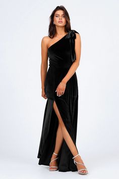 a woman wearing a black one shoulder dress with thigh high slits and an asymmetrical bow at the waist