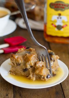 a fork is stuck into some food on a white plate with sauce and mustard in the background