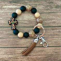 a bracelet with an animal print cross and tasseled charm on it, sitting on top of a wooden table