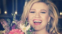 a woman holding a bouquet of flowers in front of her face and smiling at the camera