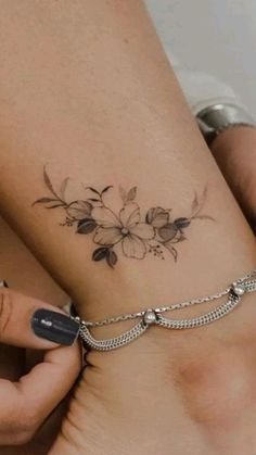 a woman with a tattoo on her arm holding onto a chain that has flowers on it