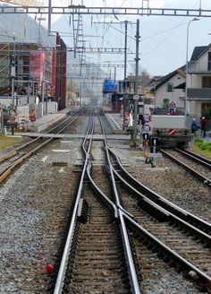 an empty train track with buildings and power lines in the backgrounds