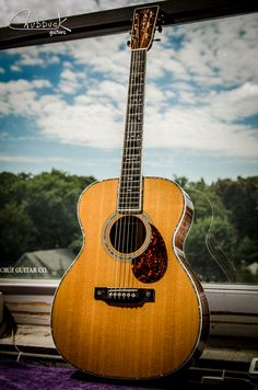 an acoustic guitar sitting on top of a window sill