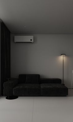 a black couch sitting next to a window in a living room with a lamp on top of it