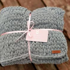 two gray crocheted blankets wrapped in pink ribbon with a tag on the end