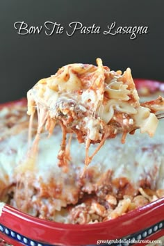 a red bowl filled with lasagna covered in sauce and cheese, being lifted from the casserole dish