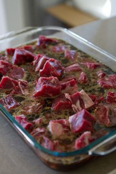 a casserole dish filled with meat and seasoning on top of a table