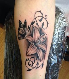 a black and white photo of a flower with butterflies on its leg, next to a tattoo design